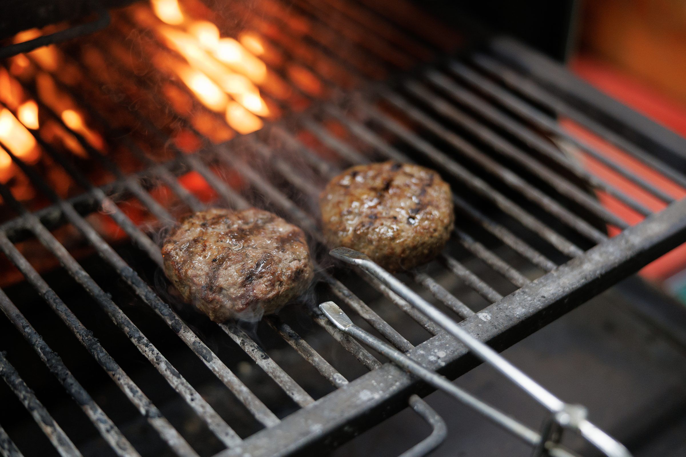 Burger patties on a flaming grill