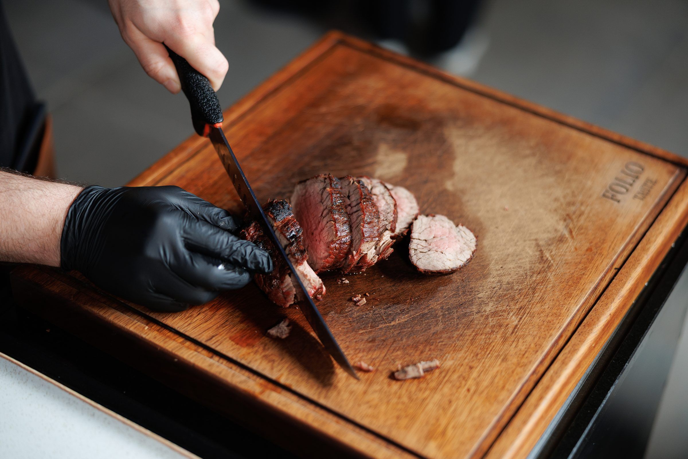 A chef slicing a grilled steak on a wooden board