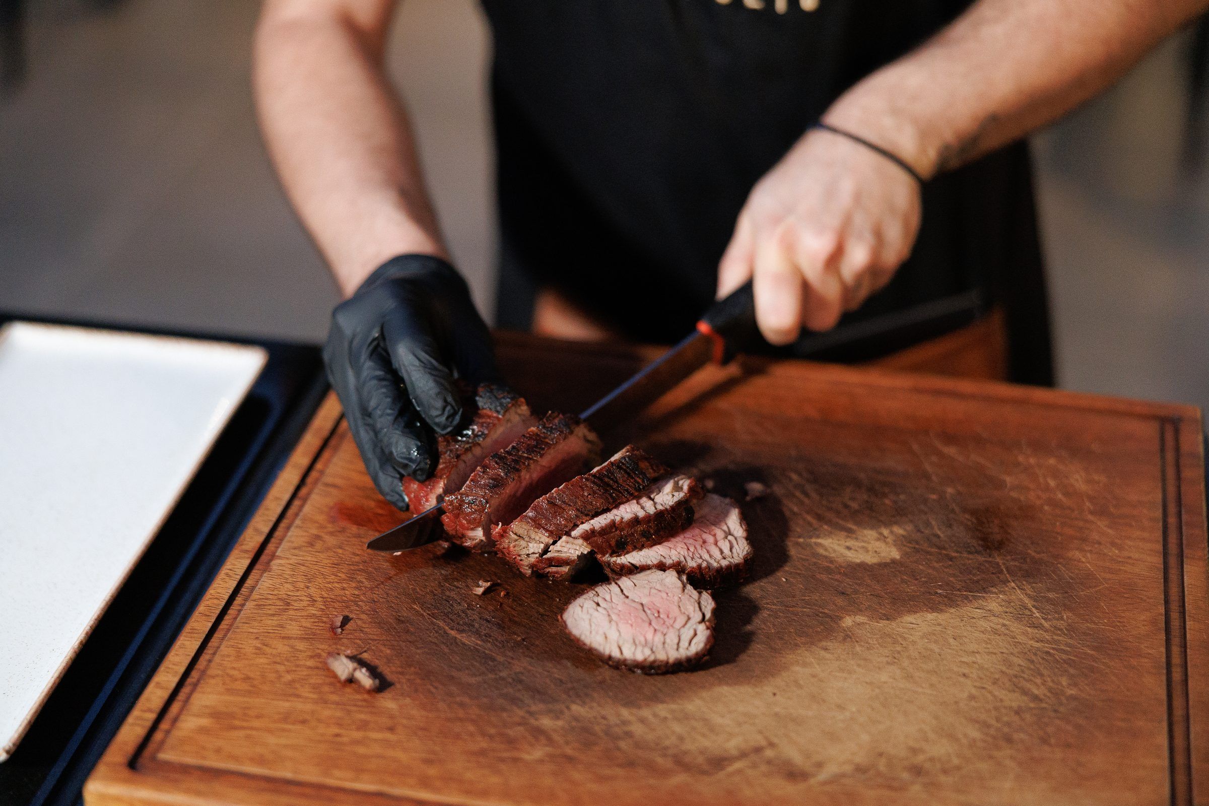 A chef slicing steak on a wooden board